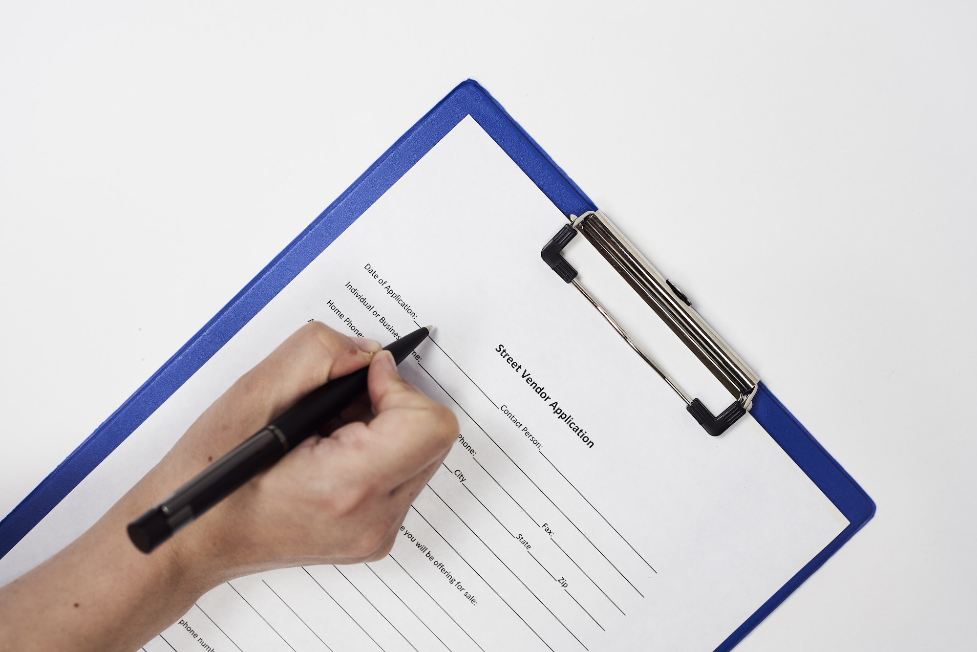Closeup of a person signing a Street Vendor Application Form